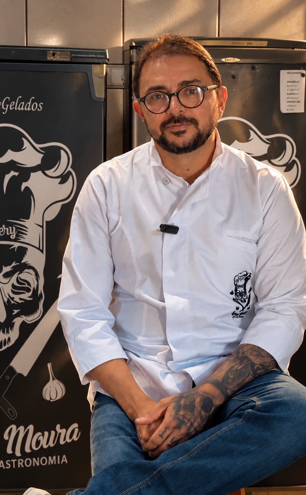 Chef Luciano Moura de jaleco branco, sentado na cozinha da Luciano Moura Gastronomia em Pelotas