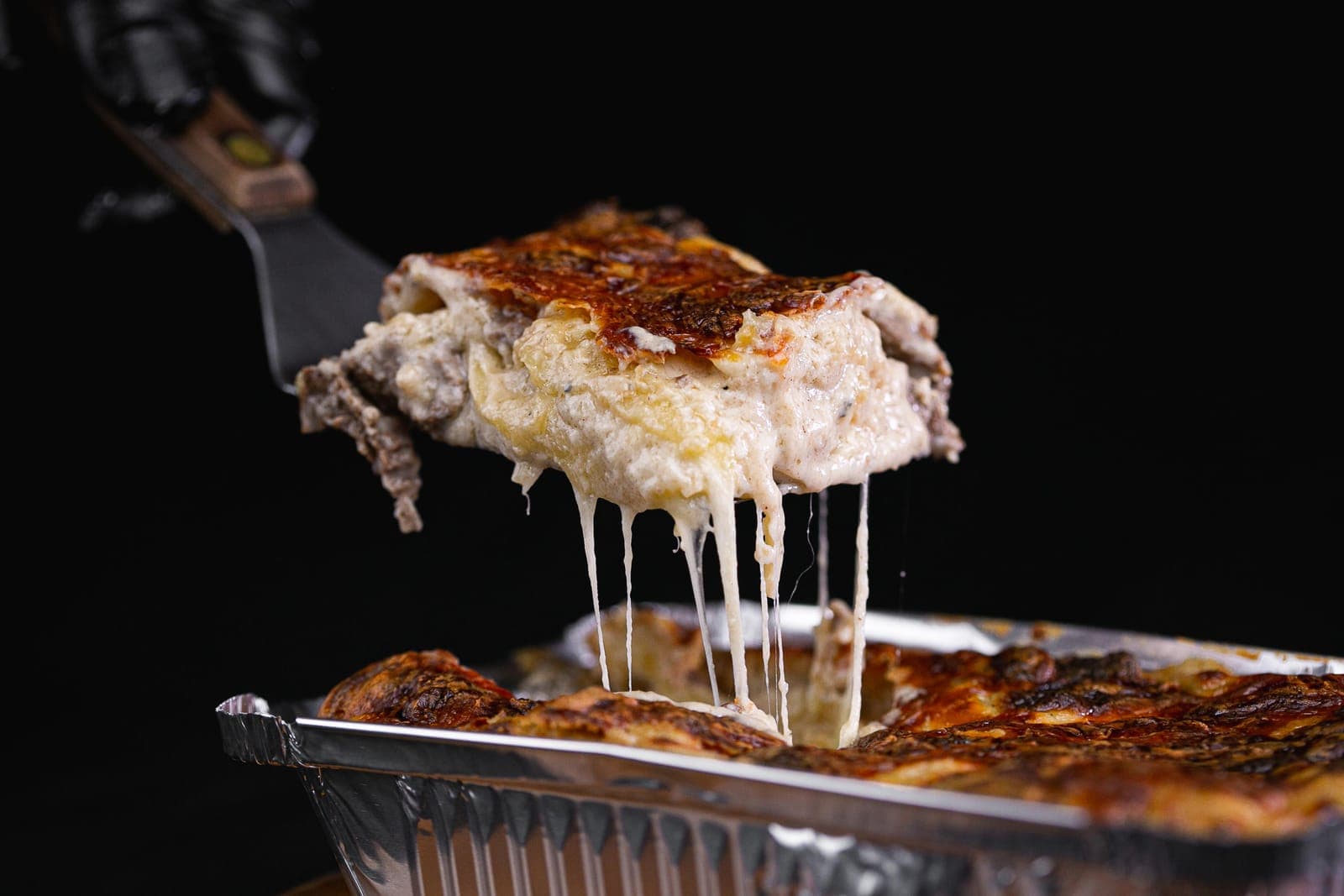 Porção de lasanha de carne com fios de queijo derretido